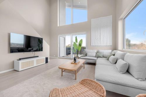 a living room with a couch and a tv at Sunset Bay Penthouse in Kristiansand