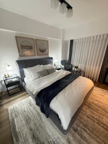 a bedroom with a large bed with white sheets and a rug at Garsoniera G 5 in Roman