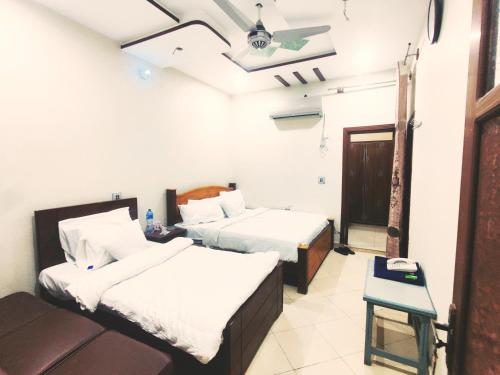 a room with two beds and a couch in it at Al Hidayah Hotel Multan in Multan