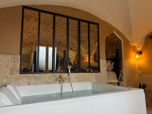a bath tub in a room with a window at Les Voûtes Secrètes - Love Room avec Balnéo à Bras in Bras