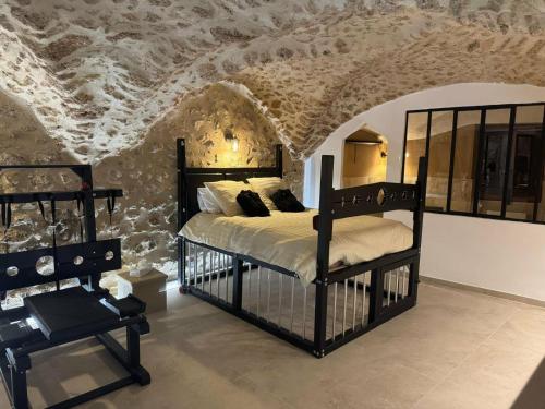 a bedroom with a bed and a stone wall at Les Voûtes Secrètes - Love Room avec Balnéo à Bras in Bras