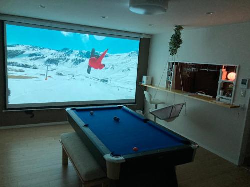 a large screen with a pool table in front of a tv at Lhouseー遊べる宿ビリヤード 大型スクリーン 岡山駅徒歩15分 in Okayama