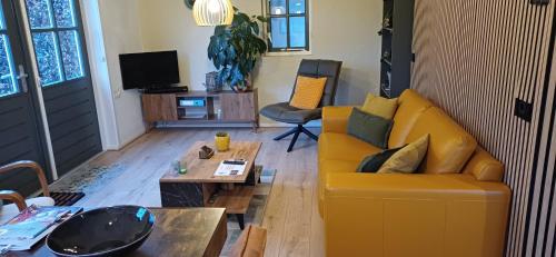a living room with a yellow couch and a coffee table at Bed & Breakfast Appenseweg in Voorst