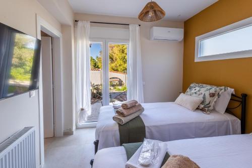 a room with two beds and a window with a balcony at Villa Keyd Mare in Porto Rafti