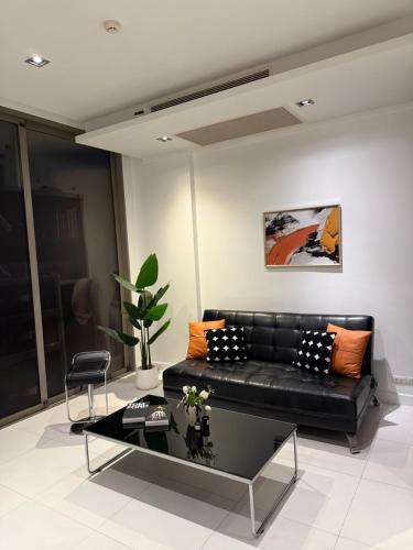 a black leather couch in a living room with a table at Modus Pattaya Beachfront Apartment in North Pattaya