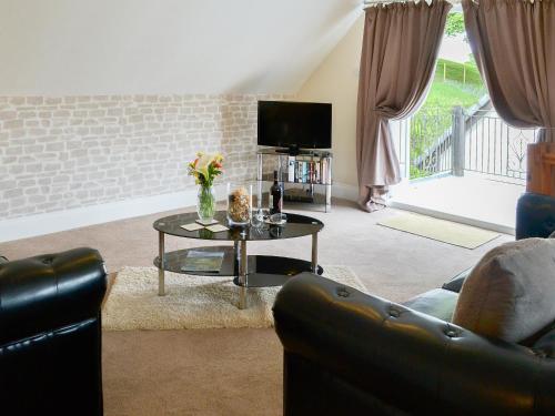 a living room with a couch and a table with a tv at Rosecraddoc Manor - Lakeview in Saint Cleer