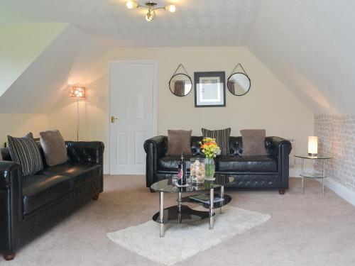 a living room with two black leather couches and a table at Rosecraddoc Manor - Lakeview in Saint Cleer
