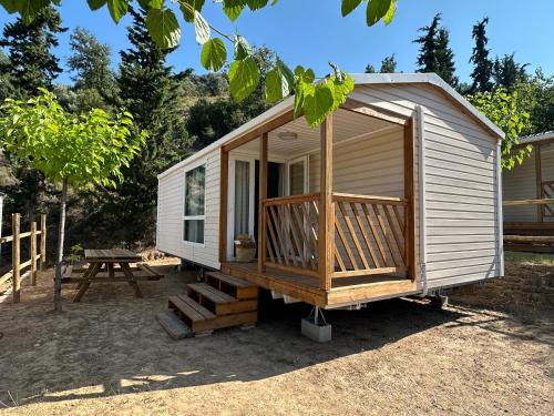 a tiny house with a porch and a picnic table at Camping Rio Vero de Alquézar in Alquézar