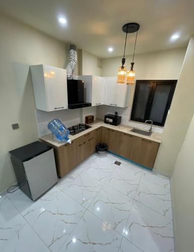 a kitchen with white cabinets and a white tile floor at Riverhills Comfort 2BHK in Rawalpindi