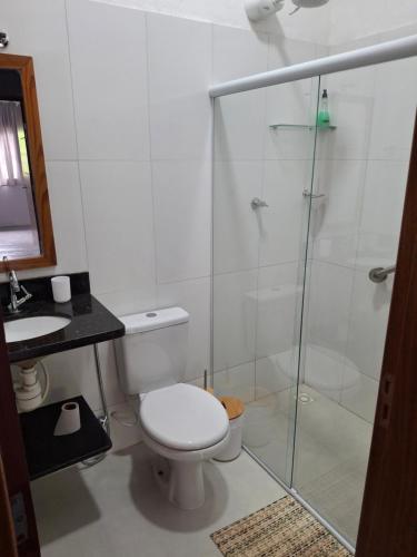 a bathroom with a toilet and a glass shower at Casa na praia prática aconchegante in Serra