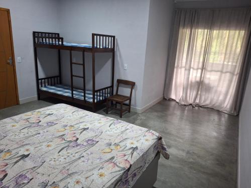 a bedroom with a bed and a chair and a window at Casa na praia prática aconchegante in Serra