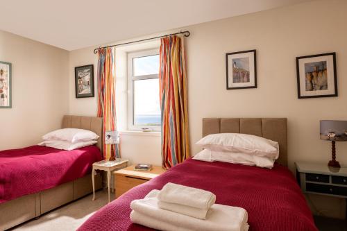 a bedroom with two beds and a window at Self-catering Lighthouse Keeper's Cottage on the NC500 in Wick