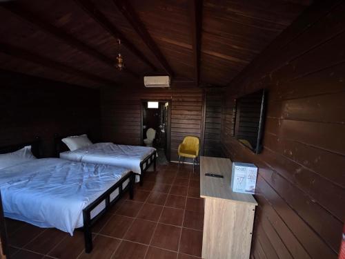 a room with two beds and a yellow chair at Auberge RAMZ'S in Beni Mellal