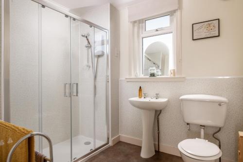 a bathroom with a shower and a toilet and a sink at Self-catering Lighthouse Keeper's Cottage on the NC500 in Wick