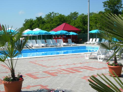 einen Pool mit Stühlen, blauen Sonnenschirmen und Stühlen in der Unterkunft Motel Imperial in Roman