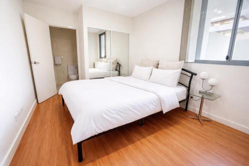 a bedroom with a large white bed with white pillows at ProHouse - Sydney Airport Wolli Creek in Sydney