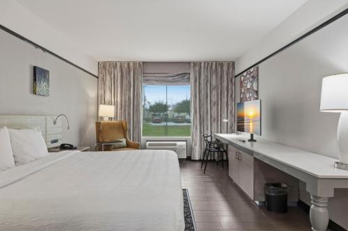a hotel room with a bed and a desk and a window at Kozy Hotel Houston North in Westfield