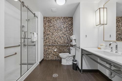 a bathroom with a toilet and a sink and a shower at Kozy Hotel Houston North in Westfield