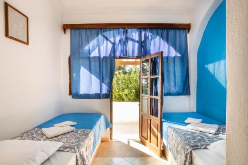 a room with two beds and a door with a window at Barbarossa Apartments in Vrachonisída Prasonísi