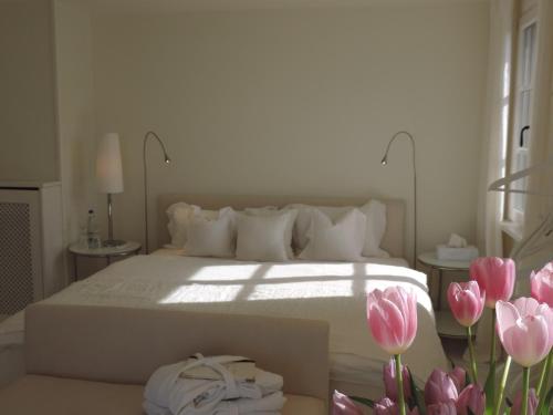 a bedroom with a white bed and pink tulips at Pension am Bodensee (Adults only) in Kressbronn am Bodensee