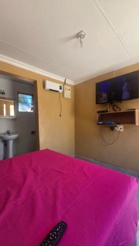 a bedroom with a pink bed with a remote control on it at 6 Tiger guest house in Katlehong