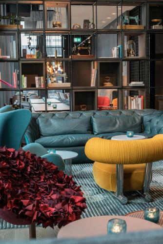 a living room with a couch and tables and shelves at Motel One Berlin-Alexanderplatz in Berlin
