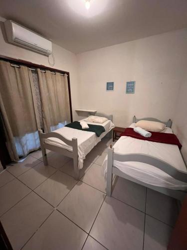 a room with two beds and a window in it at Casa Dourada PIPA RN - Sobrado 2 quartos in Pipa