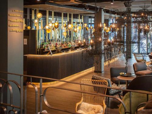a restaurant with a bar with chandeliers at Motel One Saarbrücken in Saarbrücken