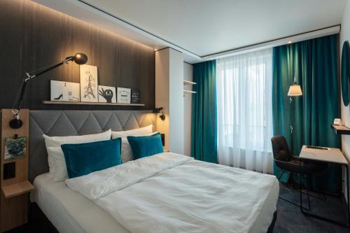 a bedroom with a large bed with blue pillows at Motel One Saarbrücken in Saarbrücken