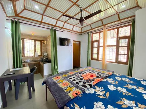 a bedroom with a bed and a desk and windows at Nagwal Hotel in Dharamshala
