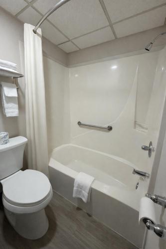 a white bathroom with a toilet and a bath tub at Dakota Inn in Minot