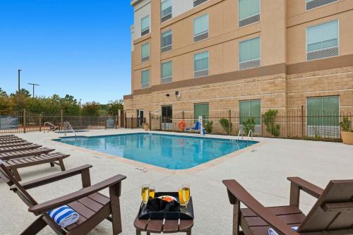 a swimming pool with two chairs and a building at Kozy Hotel Houston North in Westfield