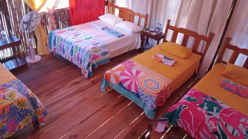 a bedroom with three beds and wooden floors at Islas de San Blas habitacion en Narasgandub in Mamartupo