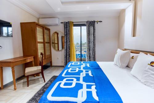 ein Schlafzimmer mit einem Bett mit einer blau-weißen Tagesdecke in der Unterkunft Helena Home - Kribi in Kribi
