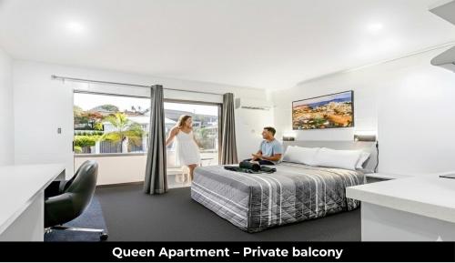 a man sitting on a bed in a hotel room at Aaron Motel in Gladstone