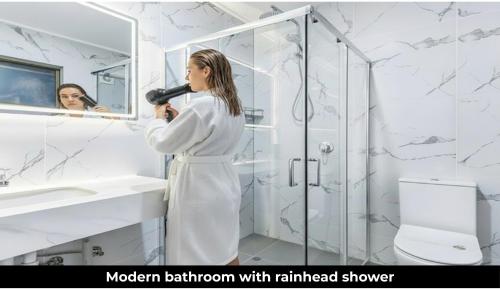 a woman in a bathroom blow drying her hair at Aaron Motel in Gladstone
