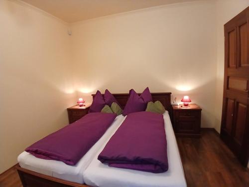 a bedroom with a large bed with purple sheets and pillows at Mami Apartman in Zalakaros