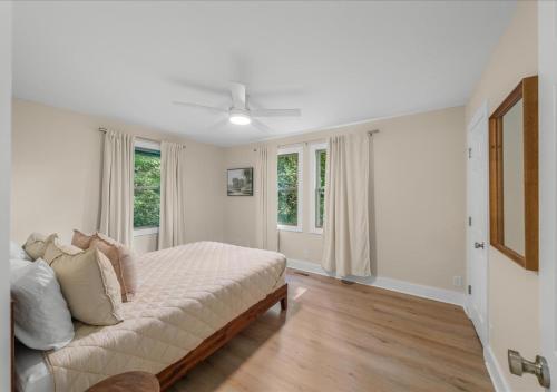 a white bedroom with a bed and two windows at Hill Top Forest Cabin with Hot Tub, Fire Pit & Screened Porch in Pigeon Forge