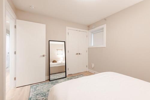 a bedroom with a white bed and a mirror at Modern Bright Suite Self Check-In in North Vancouver