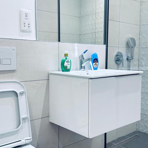 a white bathroom with a sink and a mirror at The Bantree by Tripview Apartments in Accra