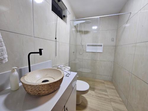 a bathroom with a stone sink and a toilet at Suíte Bem Te vi in Porto Seguro