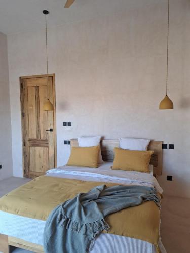 a bedroom with a large bed with yellow pillows at Villa Face a l'océan- Havre de paix & grand confort avec piscine à TOUBAB DIALAW in Rufisque
