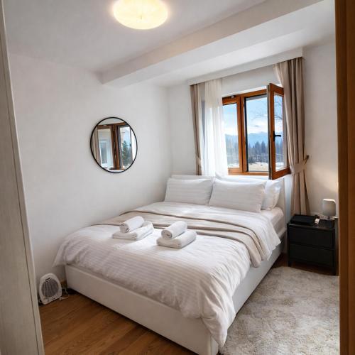 a bedroom with a large white bed with towels on it at Luxury Apartment-Aurora 33 Free Parking City Center in Podgorica