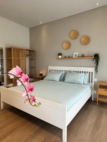 a bedroom with a white bed with pink flowers on it at Lioravilla21 Kota Baru Parahyangan in Padalarang