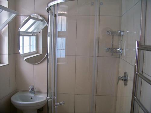 a bathroom with a shower and a sink and a mirror at Jetty Self-Catering in Swakopmund