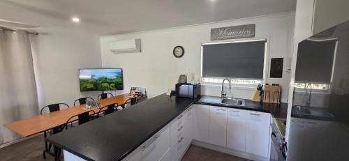 a kitchen with white cabinets and a black counter top at Family Cozy House near the Bay and the Reserve in Golden Beach