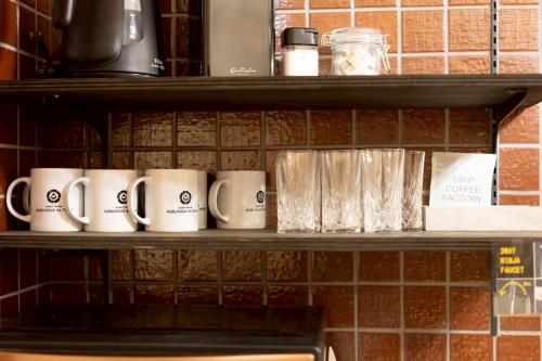 a row of coffee mugs sitting on a shelf at 旅宿信長と忍者---1階-信長の間---NOBUNAGAtoNINJA in Omihachiman
