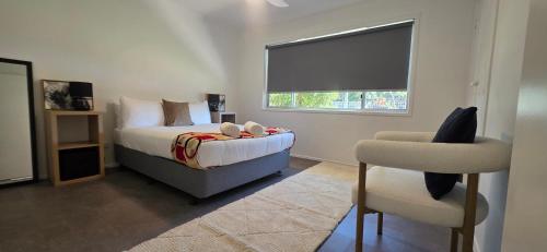 a bedroom with a bed and a chair and a window at Family Cozy House near the Bay and the Reserve in Golden Beach