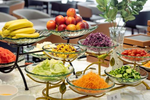 a buffet of bowls of vegetables and fruit on a table at Atour Hotel Dalian Xinghai Square in Dalian