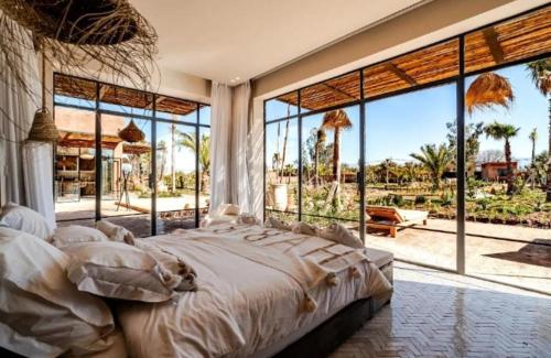 a bedroom with a large bed and large windows at villa Bohème Chic in Had Abdallah Rhiat